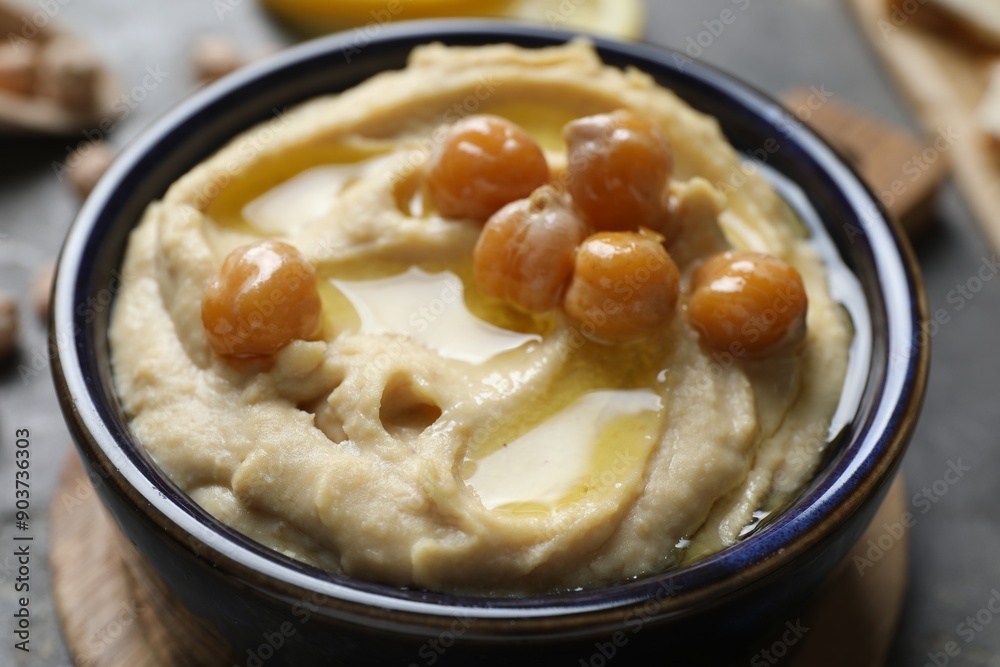 Delicious hummus with olive oil and chickpeas in bowl on grey table, closeup Delicious hummus with olive oil and chickpeas in bowl on grey table, closeup