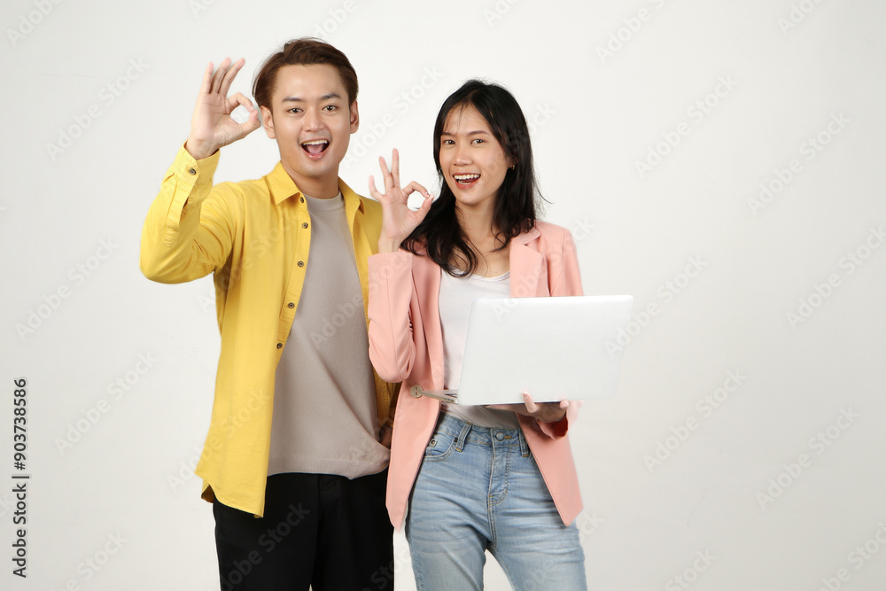 portrait of happy asian Indonesian couple holding laptop computer and giving ok sing finger gesture on isolated background portrait of happy asian Indonesian couple holding laptop computer and giving ok sing finger gesture on isolated background