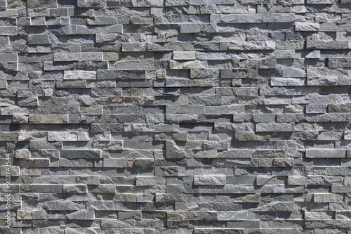 Stone coating wall made of striped stacked bricks of natural gray rocks. External wall covering, background and texture.	