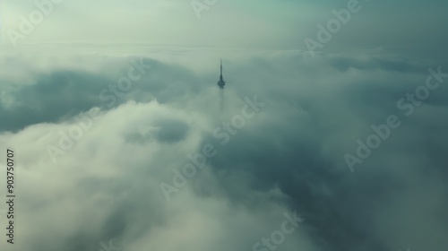 Solitary tower emerging through thick cloud cover at dawn