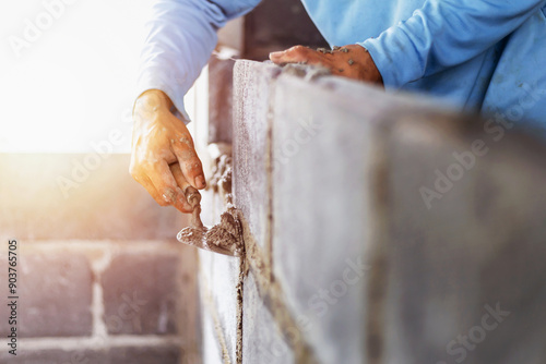Construction workers are building cement walls with brick blocks.
