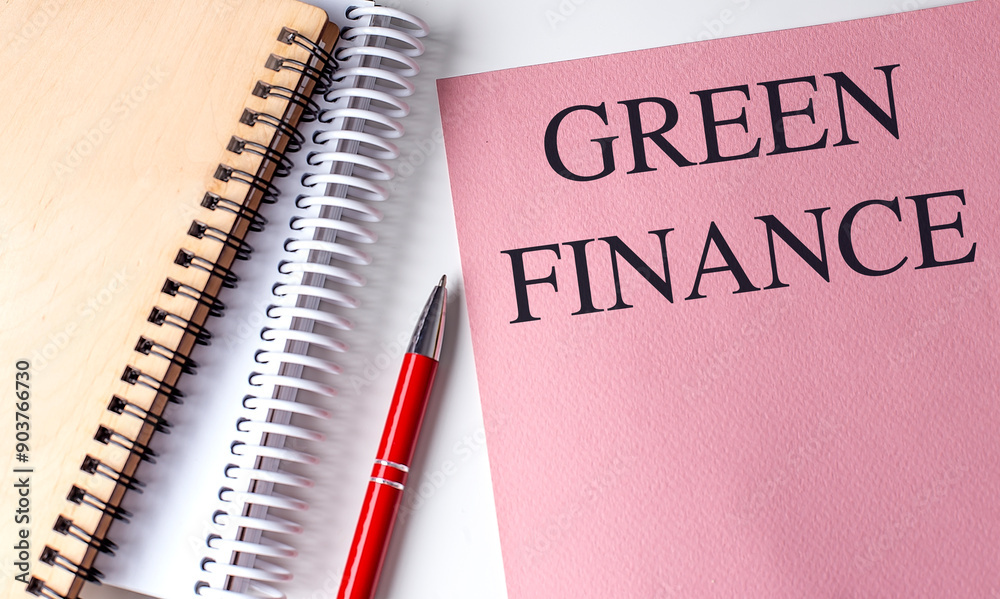 GREEN FINANCE text on pink paper with notebooks GREEN FINANCE text on pink paper with notebooks