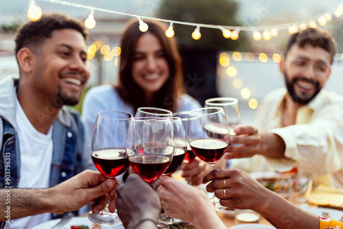 Bild auf Leinwand Group of young people toasting red wine at rooftop night party