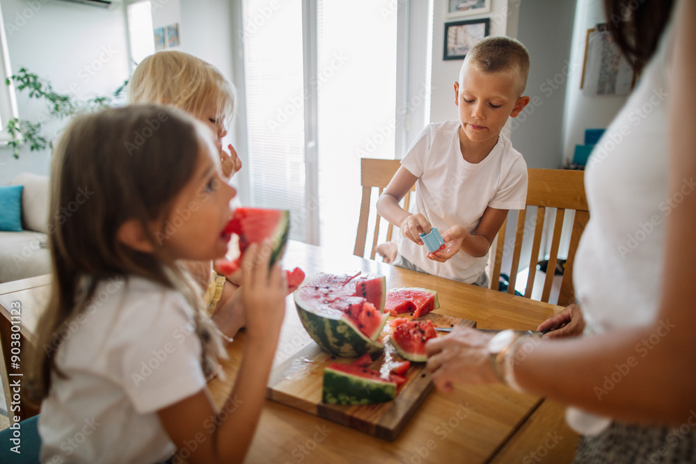 Kids delight in juicy watermelon slices at dinning table Kids delight in juicy watermelon slices at dinning table