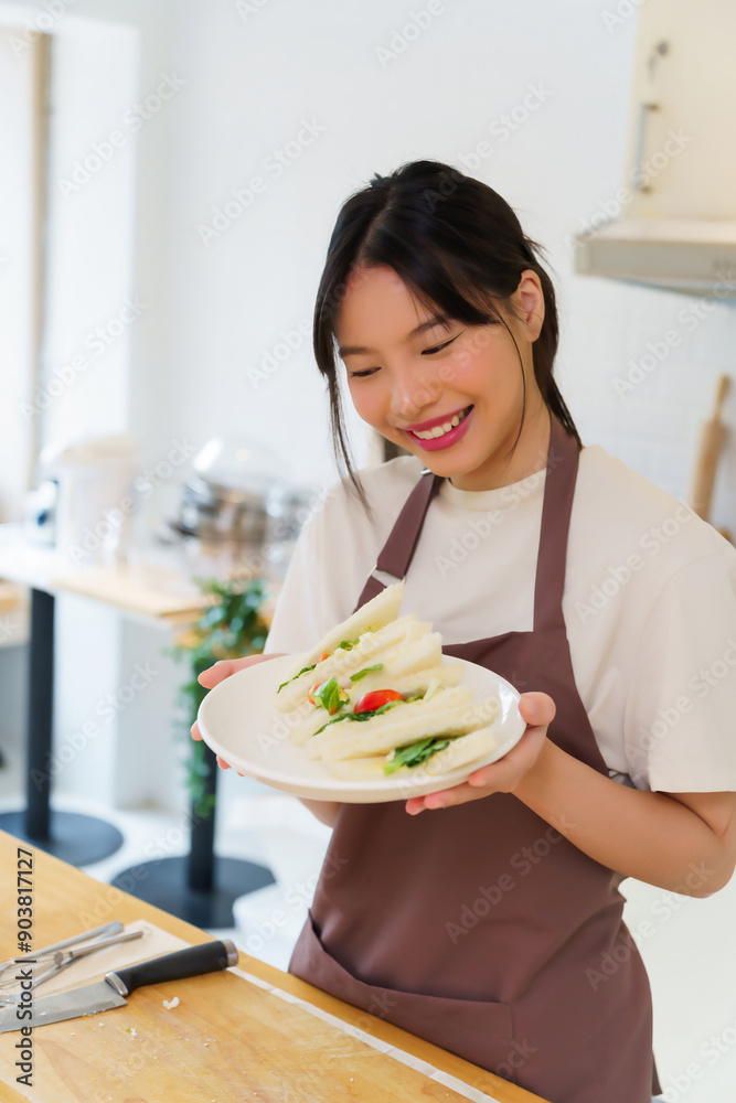 Asian women holding plate of delicious sandwich after making sandwich with boiled egg salad and fresh vegetable while cooking breakfast meal and making healthy food lifestyle in the kitchen at home Asian women holding plate of delicious sandwich after making sandwich with boiled egg salad and fresh vegetable while cooking breakfast meal and making healthy food lifestyle in the kitchen at home
