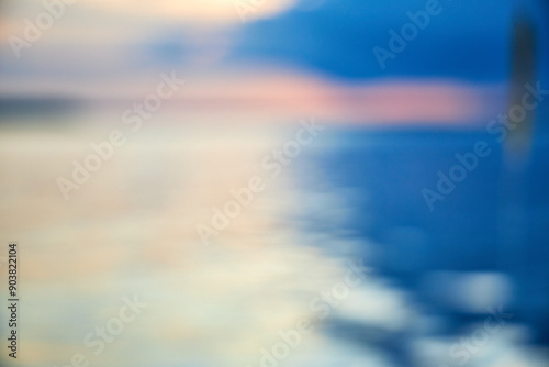 blurred background view of summer sunset with the reflection of the sun on the river