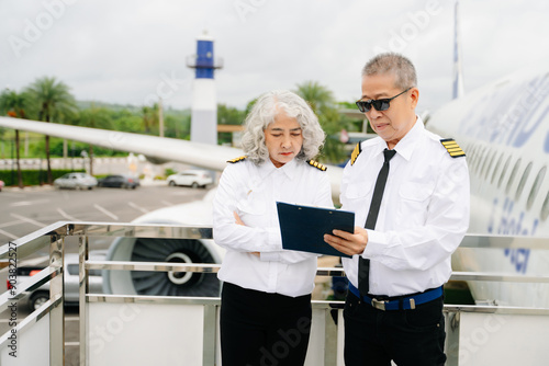 Mature commercial male pilot Beautiful middle aged woman airplane captain instructor has a meeting, discussion with aircrew team