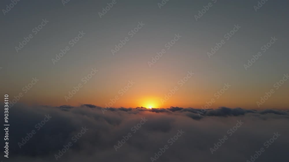 View from an airplane during sunset, flying above the clouds. The orange sun's rays light up the View from an airplane during sunset, flying above the clouds. The orange sun's rays light up the