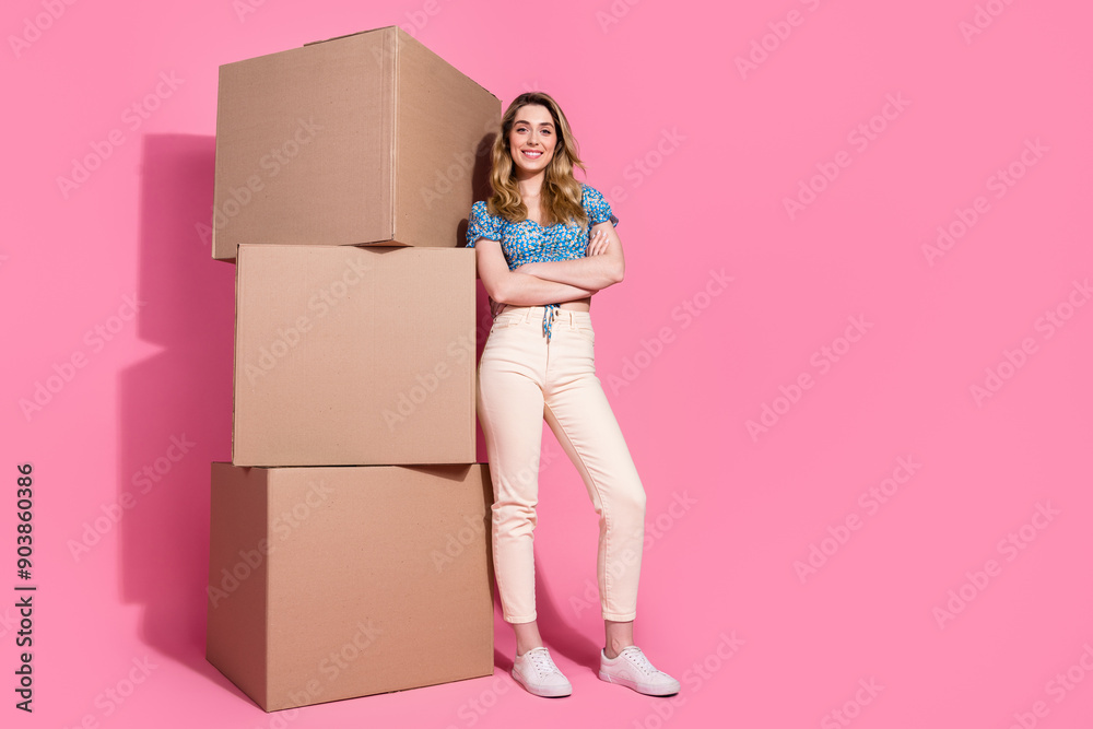 Full size photo of pretty young girl carton box stack crossed hands wear trendy blue flower print outfit isolated on pink color background Full size photo of pretty young girl carton box stack crossed hands wear trendy blue flower print outfit isolated on pink color background