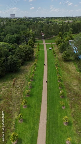 Wide aerial dolly shot of Newlands walking path towards Campbell Park, with trees on either side. Fourteen Sky Bar in the background