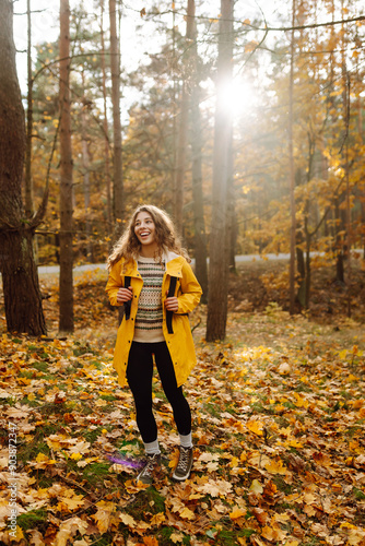 Smiling young woman enjoys the autumn weather in the forest. Autumn landscape.