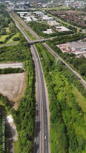 Aerial dolly shot of th A5 road, Milton Keynes Central, with cars driving on it. Train to the right is approaching Milton Keynes Train Station
