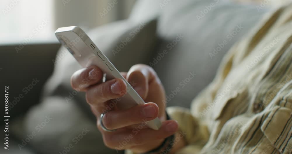 A man is typing on a mobile phone sitting on the couch at home. close-up of his hands, an unrecognizable person. Daylight A man is typing on a mobile phone sitting on the couch at home. close-up of his hands, an unrecognizable person. Daylight