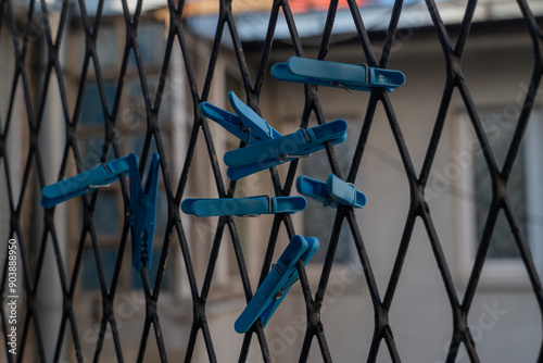 a lot of blue clothespins are attached to a metal grid. Blue clothespins for drying clothes. High quality photo