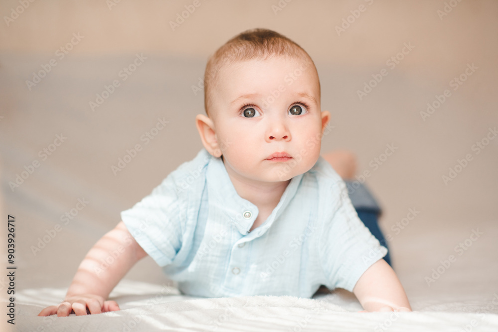Cute infant baby boy 3-4 months old crawling in bed wearing blue stylish onesie close up. Childhood. Cute infant baby boy 3-4 months old crawling in bed wearing blue stylish onesie close up. Childhood.