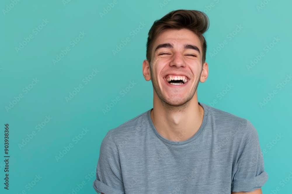 Fototapeta premium Young adult man laughing against solid color background