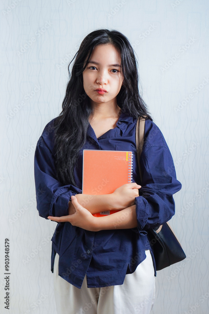 Sad and disappointed young Asian woman student holding book. concept photo back to school or campus Sad and disappointed young Asian woman student holding book. concept photo back to school or campus