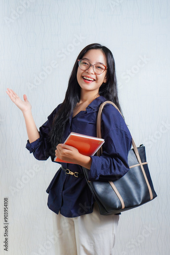 Excited happy young Asian woman student holding book wearing moody glasses. concept photo back to school or campus