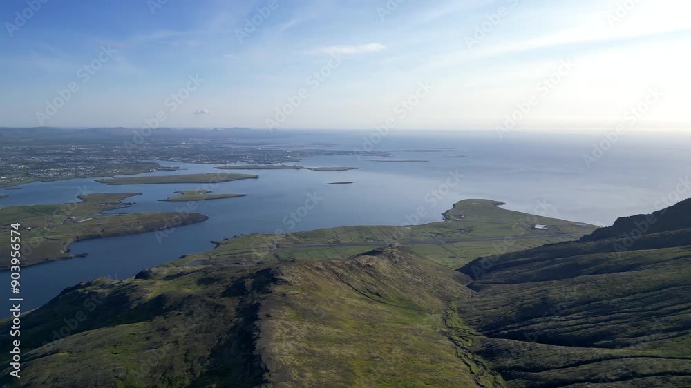 A breathtaking aerial view taken by a drone showcasing a serene landscape with rolling green hills descending towards a calm coastal area. The image captures the vast expanse of the sea. A breathtaking aerial view taken by a drone showcasing a serene landscape with rolling green hills descending towards a calm coastal area. The image captures the vast expanse of the sea.