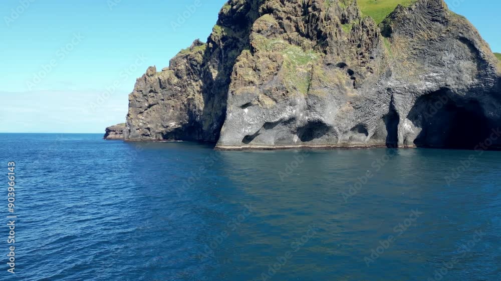 A drone image of Elephant Rock in Iceland. The striking basalt formation resembles an elephant's head dipping into the deep blue ocean, with clear skies adding to the stunning natural beauty. A drone image of Elephant Rock in Iceland. The striking basalt formation resembles an elephant's head dipping into the deep blue ocean, with clear skies adding to the stunning natural beauty.