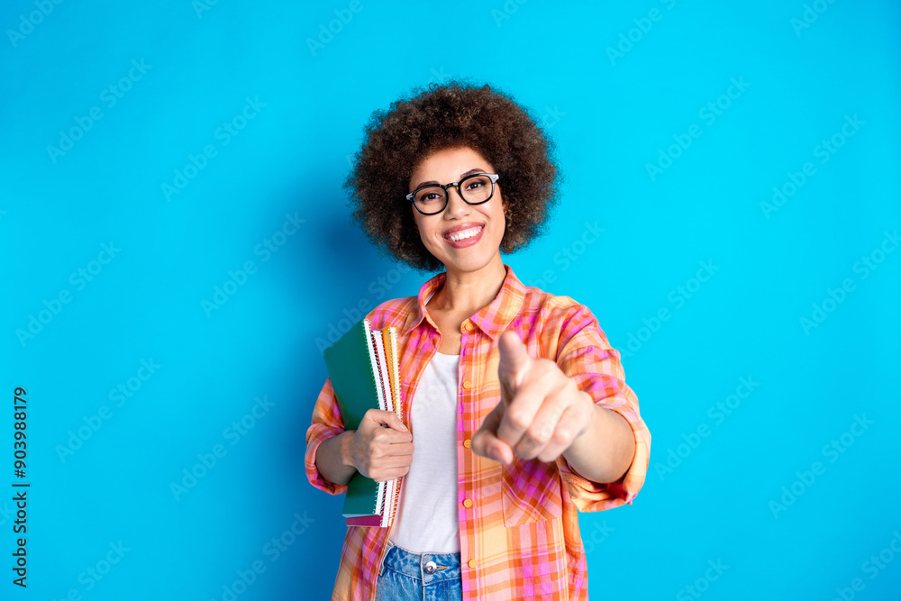 Photo portrait of attractive young woman hold copybooks point you dressed stylish checkered clothes isolated on blue color background Photo portrait of attractive young woman hold copybooks point you dressed stylish checkered clothes isolated on blue color background