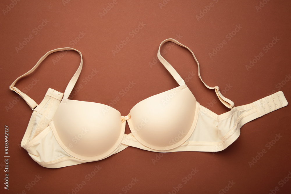 Beige female bra on brown background. Compression bra for breast. Top view Beige female bra on brown background. Compression bra for breast. Top view