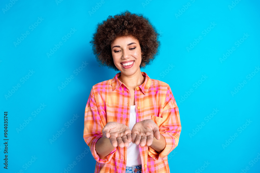 Photo portrait of lovely young lady look hold empty space dressed stylish checkered garment isolated on blue color background Photo portrait of lovely young lady look hold empty space dressed stylish checkered garment isolated on blue color background