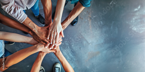 A circle of diverse people putting hands together in unity with room for text or copy space. Cooperation, collaboration, partnership, teamwork concept.
