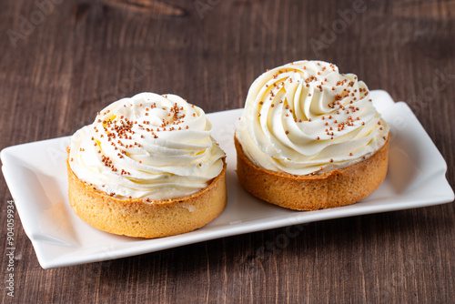 Fotografie Lemon tartlets with whipped cream, sprinkles and chocolate chips on white backgr