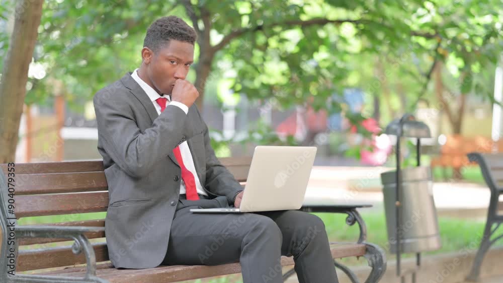 African Businessman Coughing with Laptop in Lap Outdoor African Businessman Coughing with Laptop in Lap Outdoor