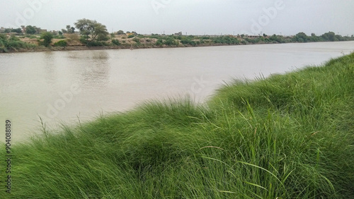 Water canal flowing with full of water with natural green grass on the bank, waterway, channel, watercourse, canal deau, canal de agua, canal deagua, wasserkanal, image stock photo  photo