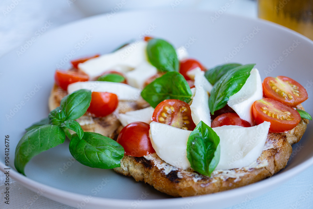 Tomato mozzarella bruschetta with basil close up on white plate - traditional italian appetizer, snack, vegetarian food, healthy eating Tomato mozzarella bruschetta with basil close up on white plate - traditional italian appetizer, snack, vegetarian food, healthy eating