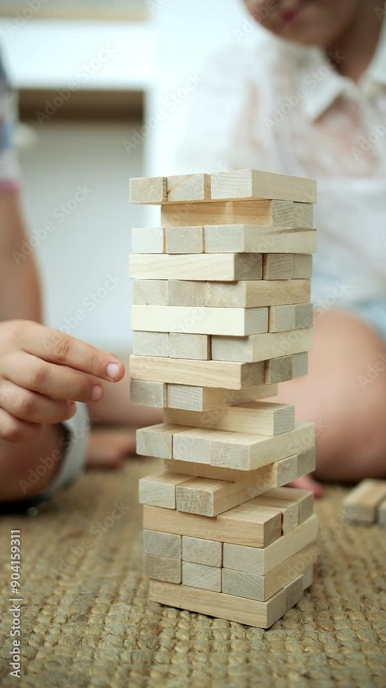 girl pulling out a brick from a jenga tower, close-up girl pulling out a brick from a jenga tower, close-up