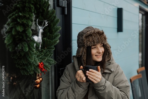 A brunette girl drinks coffee in winter. A young woman  in a hat is having fun in the winter outdour. Lifestyle photo