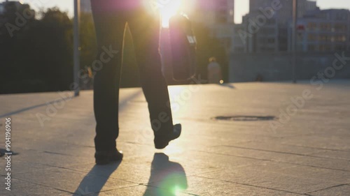 Feet of businessman with briefcase walking in city street at sunset time. Businessman commuting to work. Confident guy being on his way to office. Worker going outdoor. Rear Back view Close up