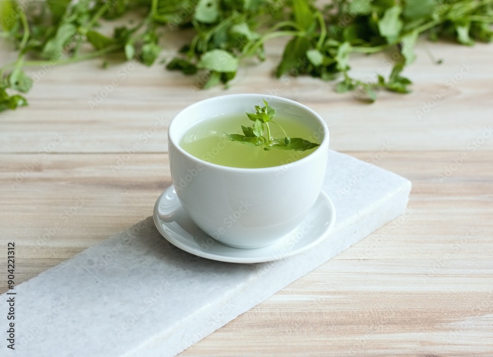 A cup of fresh tea from Chickweed, lat. Stellaria media on white marble. Traditional herb tea rich in minerals is used for detoxificatin, tasty in salads. A cup of fresh tea from Chickweed, lat. Stellaria media on white marble. Traditional herb tea rich in minerals is used for detoxificatin, tasty in salads.
