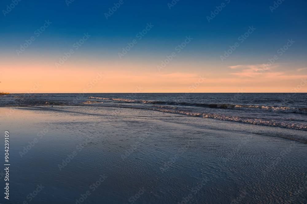 pink sky from sunset over the ocean and rolling waves on beach pink sky from sunset over the ocean and rolling waves on beach