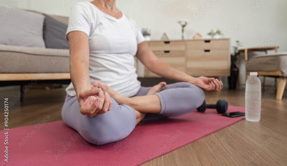 Obraz premium Elderly Woman Practicing Relaxing Yoga at Home in Comfortable Living Room Setting