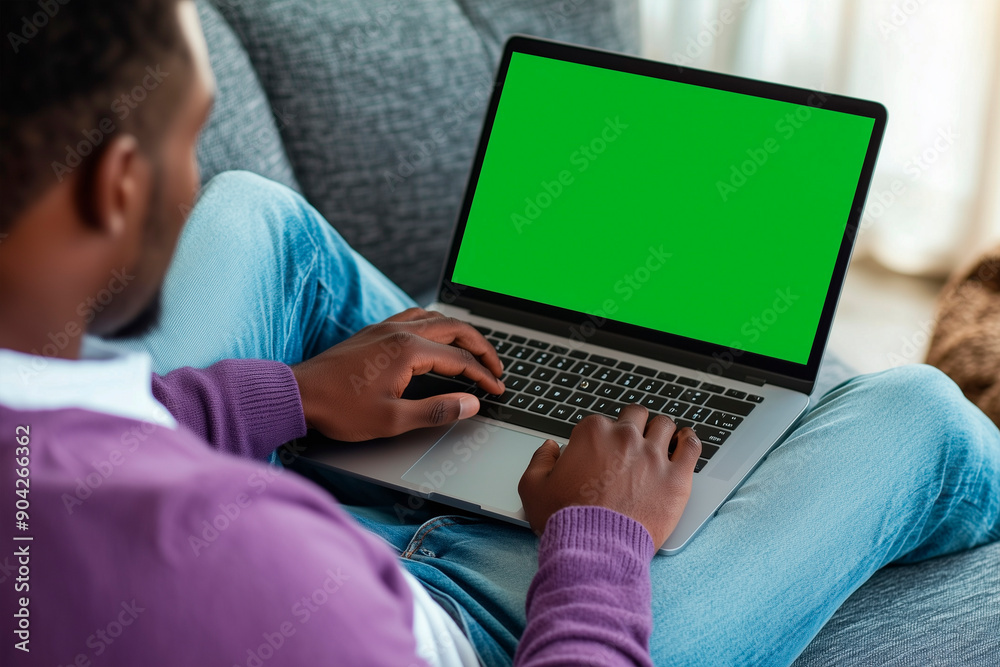 Person Sitting on Couch Working on Laptop With Blank Screen in Living Room Person Sitting on Couch Working on Laptop With Blank Screen in Living Room