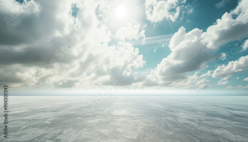 A vast expanse of a cracked, dry surface under a vibrant blue sky with scattered fluffy clouds and the shining sun overhead.