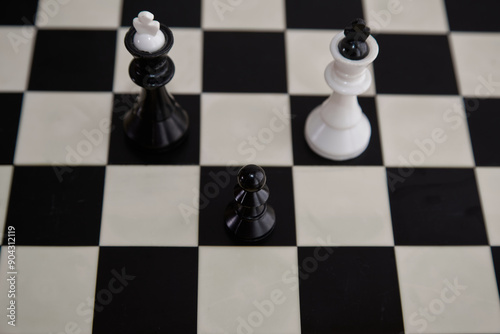 Black pawn a square ahead of black and white chess kings on a chessboard close-up, pawn and king