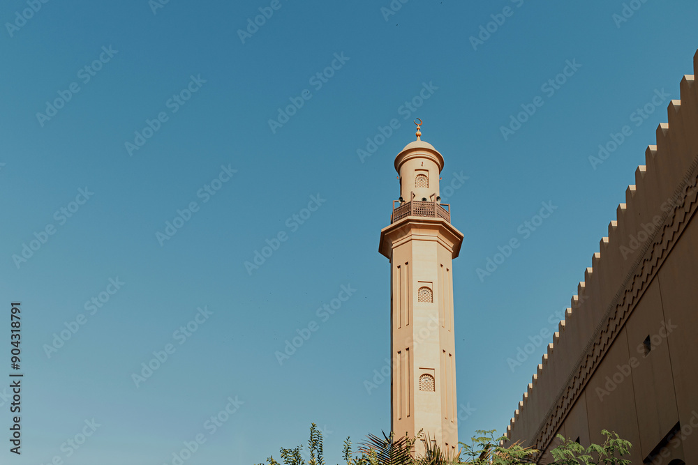 Fototapeta premium Mosque architecture on plane blue background with green tree underneath