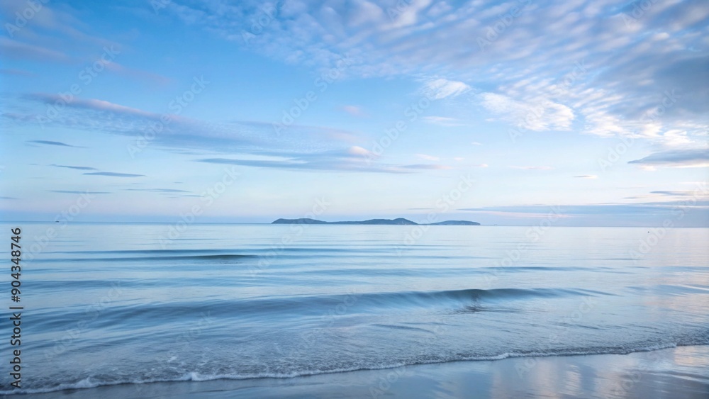 Obraz premium Calm blue ocean with a distant island under a cloudy sky.