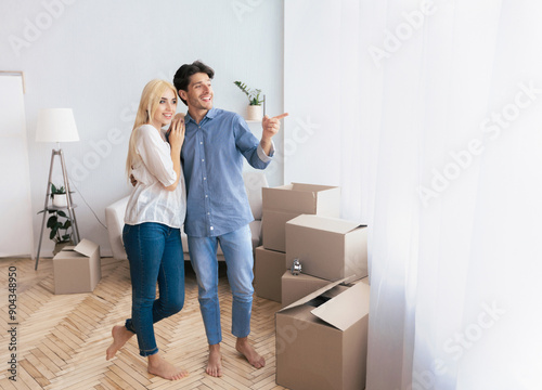 Excited Man Showing Woman View From Window In New Apartment. Moving House Concept. Free Space © Prostock-studio