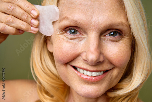 A woman is skillfully using a Gua Sha tool for a calming and rejuvenating facial massage