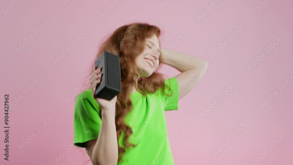 Woman dancing, enjoying on pink studio background. Girl moves to rhythm of music. Young teenager listening to music by wireless portable speaker - modern sound system. Woman dancing, enjoying on pink studio background. Girl moves to rhythm of music. Young teenager listening to music by wireless portable speaker - modern sound system.