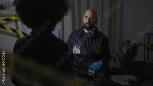 Konstfotografi Man and woman investigators analyzing evidence in a dimly-lit indoor crime scene with caution tape