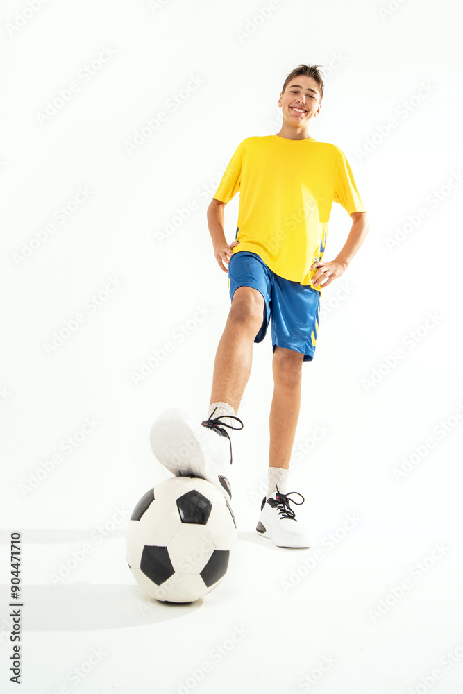 Photo of smiling teen boy in sportswear and soccer ball posing on white studio background. Photo of smiling teen boy in sportswear and soccer ball posing on white studio background.