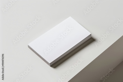 A stack of blank white paper sits on the edge of a surface, emphasizing minimalist design. The clean lines and simple presentation highlight the purity of the concept.