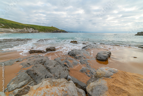 Tranquil scene of Tagle Beach in Cantabria, Spain, showcasing rugged rocks, gentle waves, and an expansive horizon. Perfect for travel, nature, and coastal themes. photo